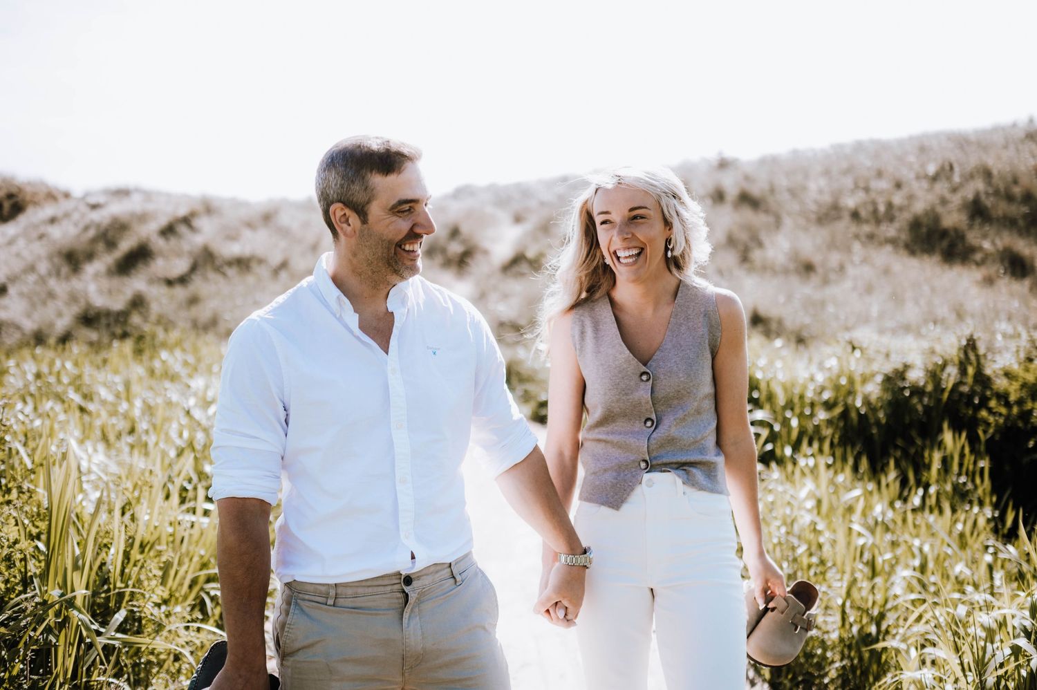 Engagement photography session Aberdeen. A romantic couple sits together in a field of wildflowers on a sunny afternoon.