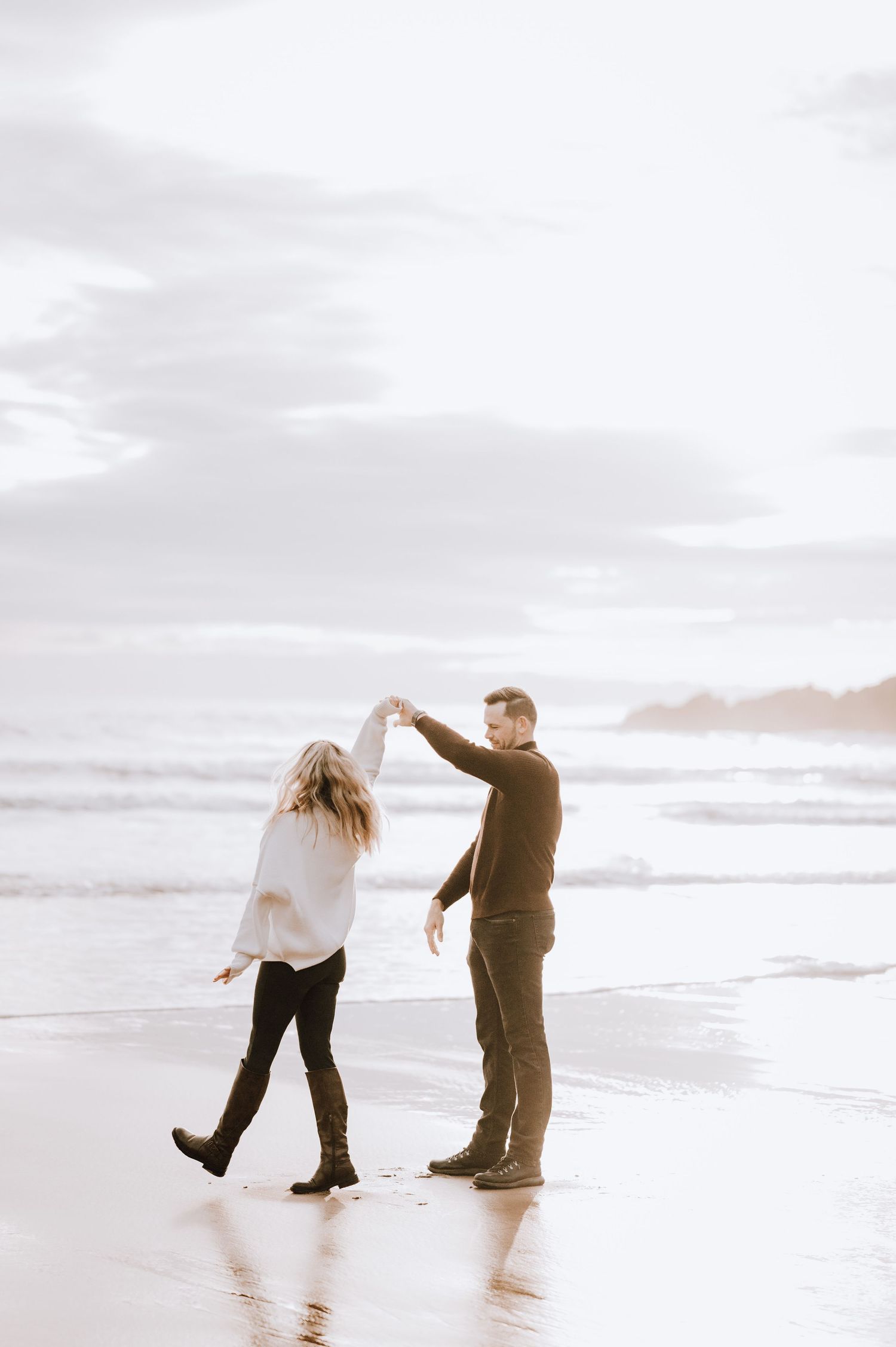 Engagement photography session Aberdeen. Two people dance together on a serene beach during golden hour.