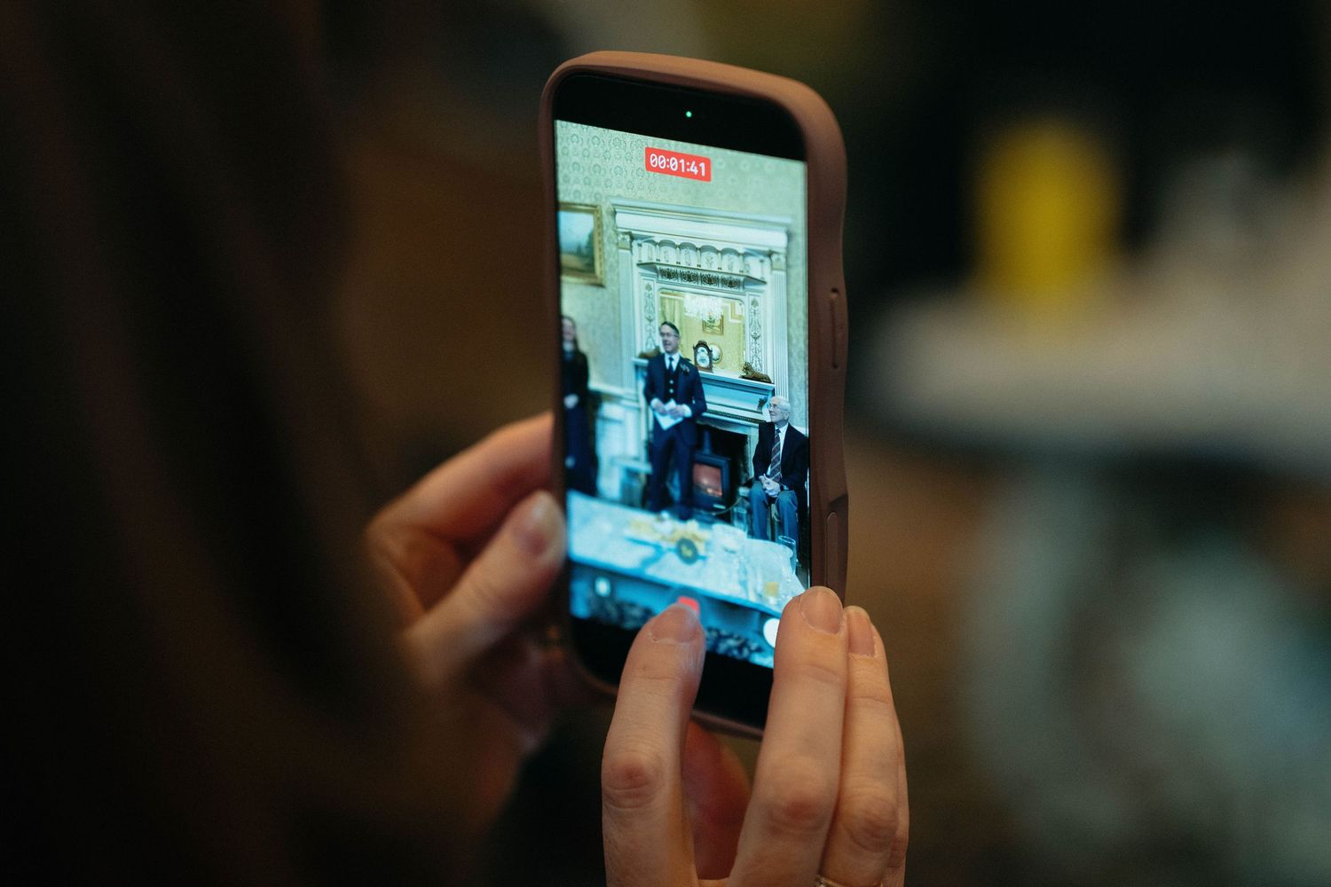Drumtochty Castle  Wedding Photography. A hand holds a smartphone capturing a social gathering through its screen.
