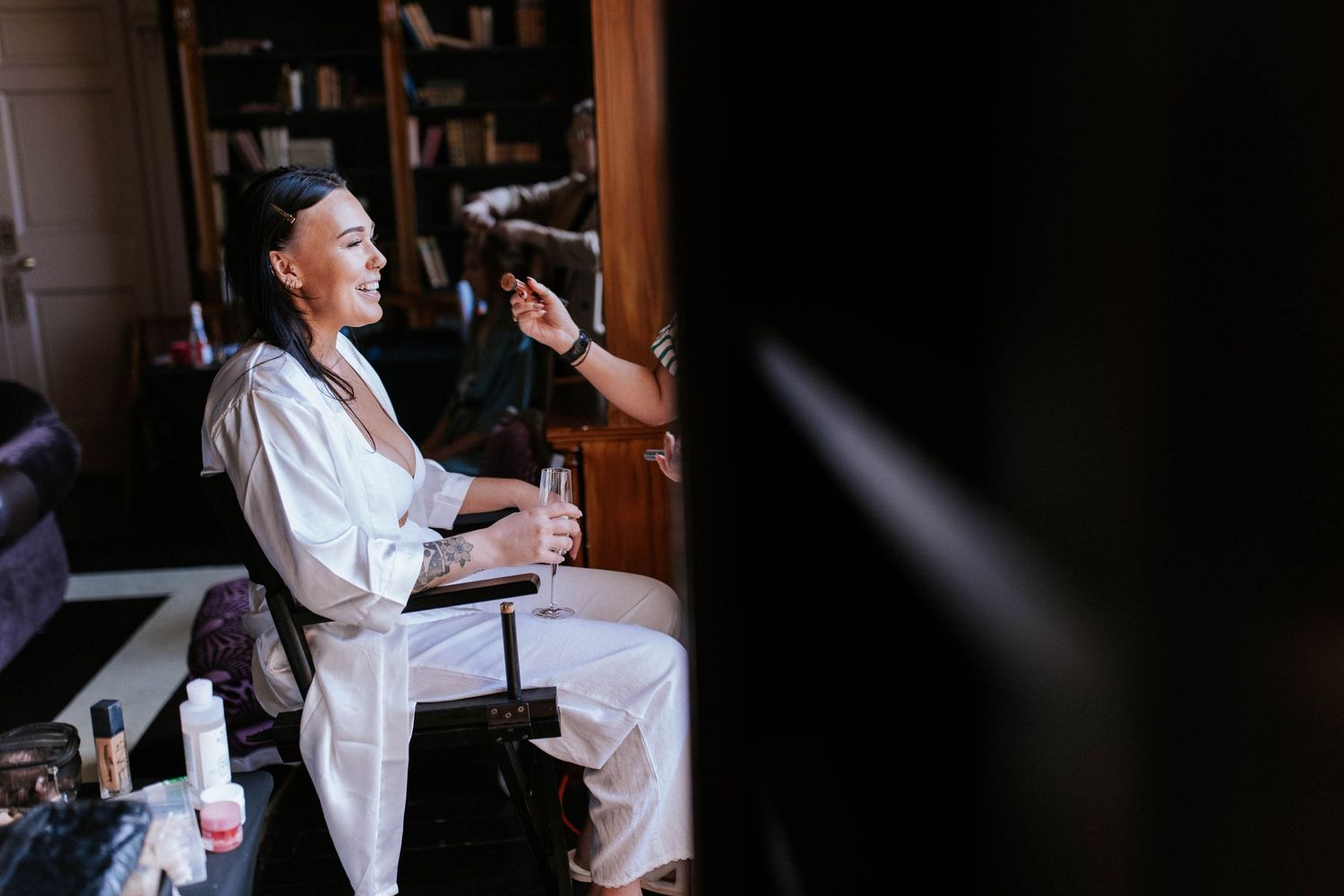 Person in white robe getting ready in a dimly lit room during wedding preparations.