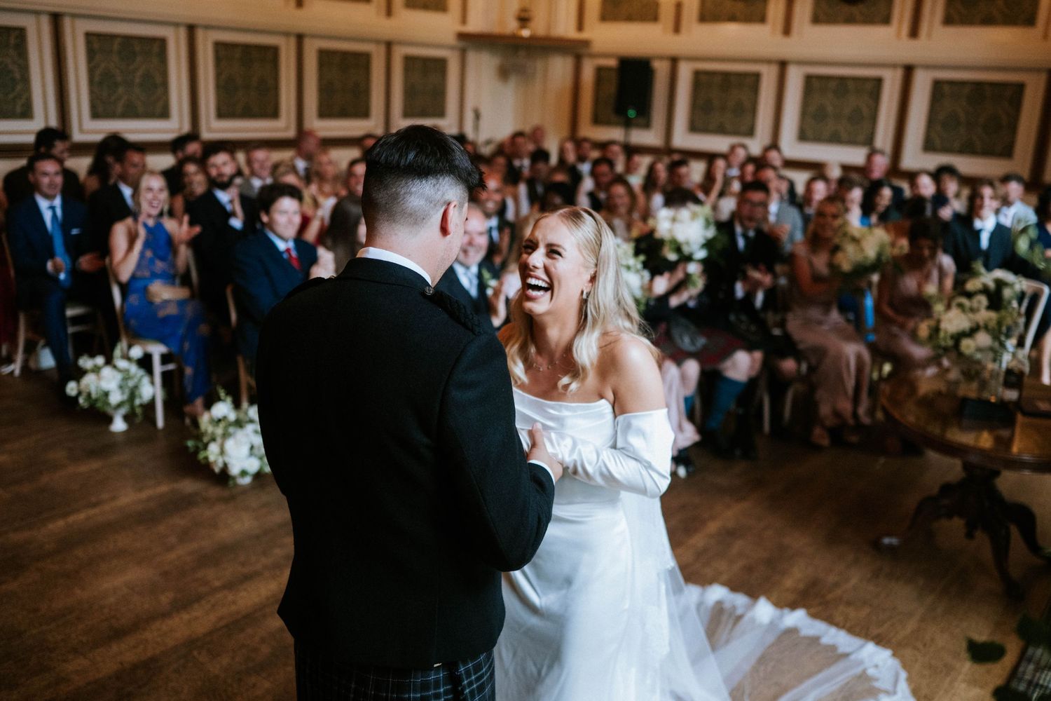 Wedding reception dance in a grand ballroom with guests watching from their seats.