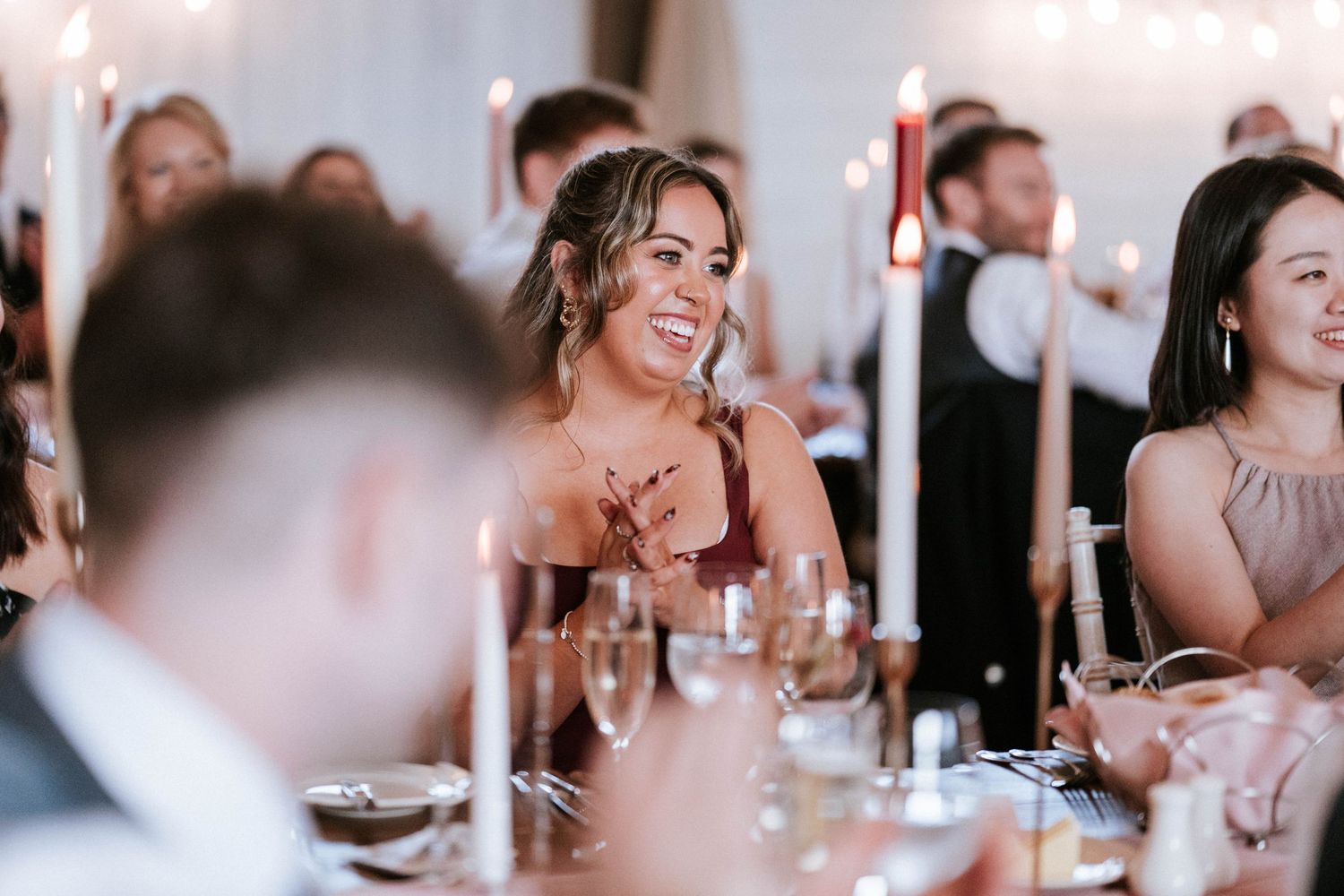 Wedding reception guests enjoying dinner and conversation at elegant table setting.