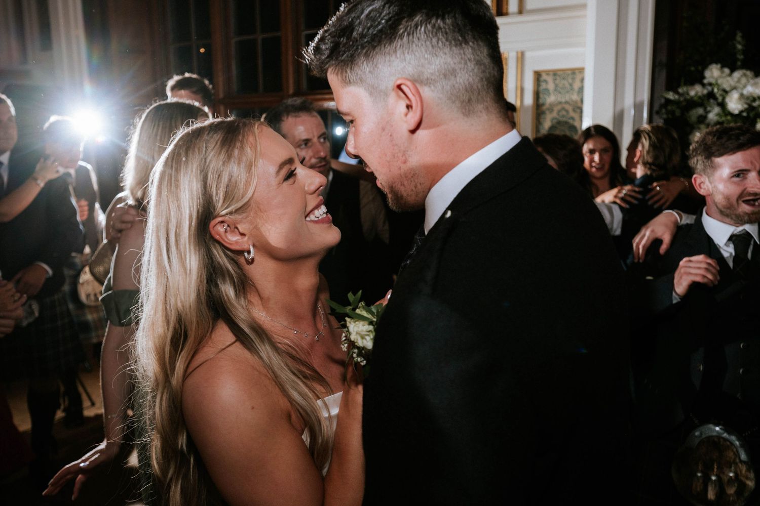 Wedding reception dance floor filled with guests celebrating under dim lighting.