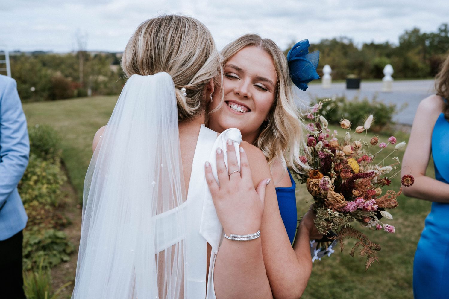 Two attendees at a wedding celebration share an emotional moment while showing off a ring.