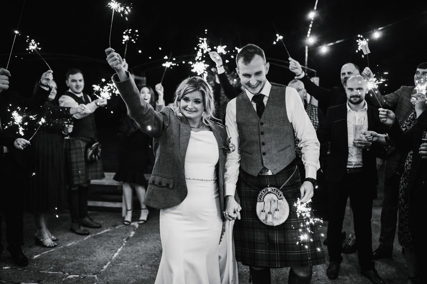 Wedding celebration at night with guests holding sparklers creating a magical atmosphere.