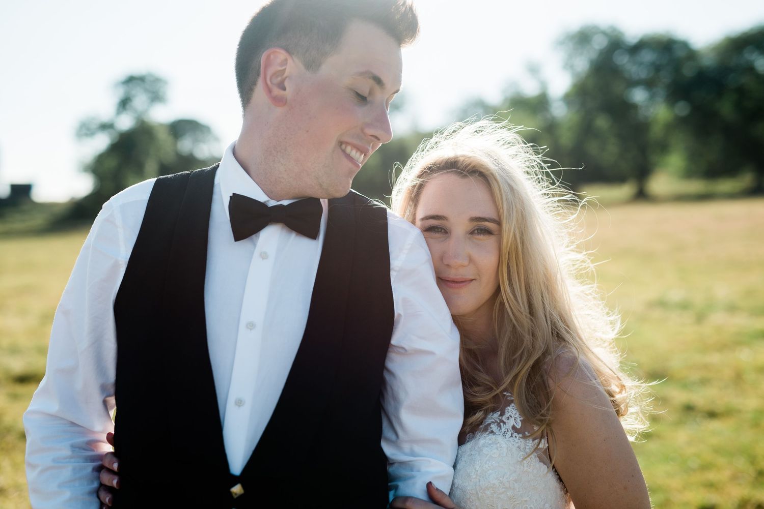 Romantic wedding couple shares intimate moments in golden sunlit field during outdoor photo session.