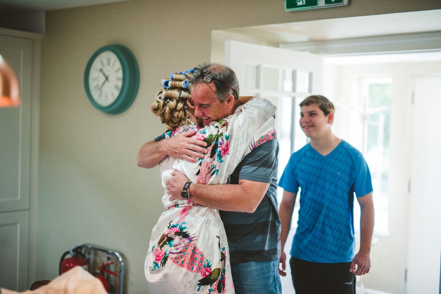 Wedding party members share emotional moments while getting ready in a bright indoor space.
