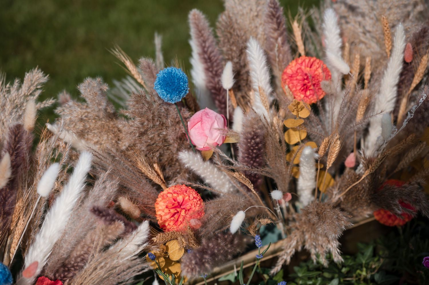 Dried pampas grass and colorful floral arrangements create a bohemian wedding decoration display.
