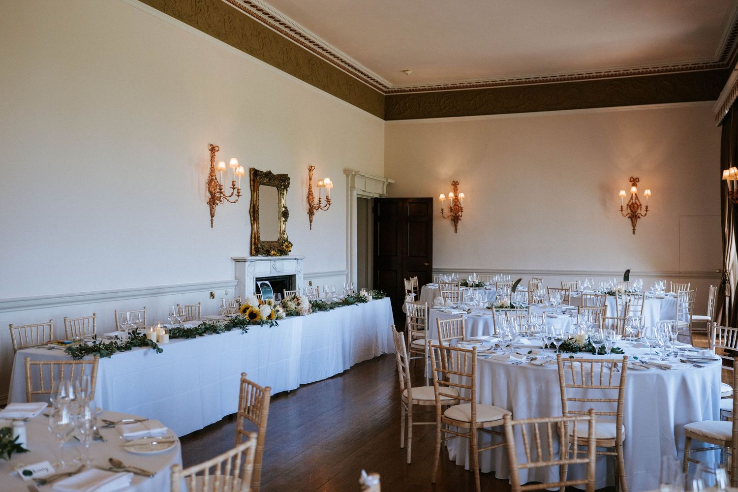 Classic wedding reception room with white tables, crystal wall sconces, and elegant decor.