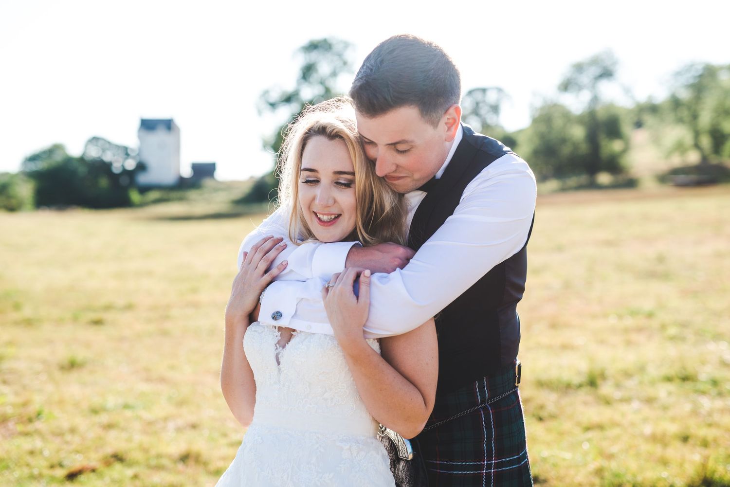 Romantic couple embraces in a sunlit field during golden hour photography session.