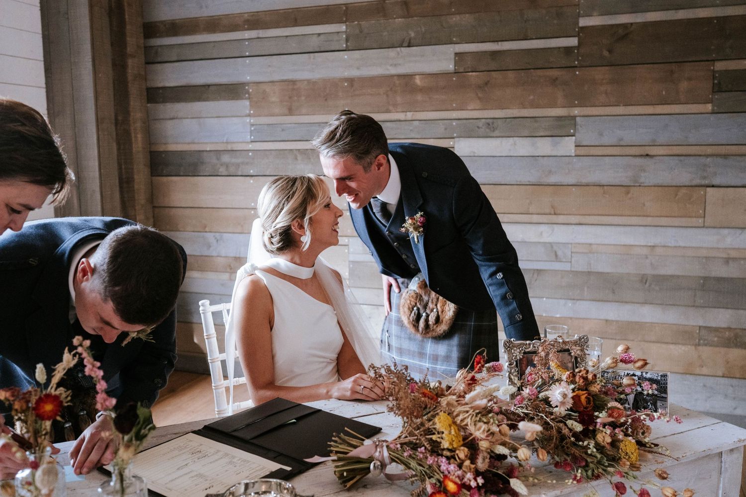 Wedding reception table setup with rustic wooden walls and elegant place settings.