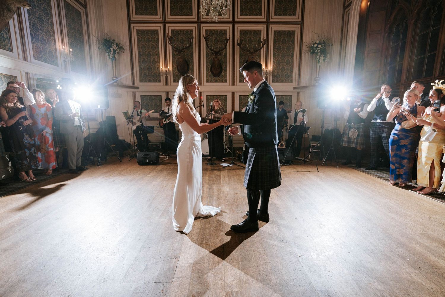 Wedding reception dance floor with guests illuminated by soft lighting.