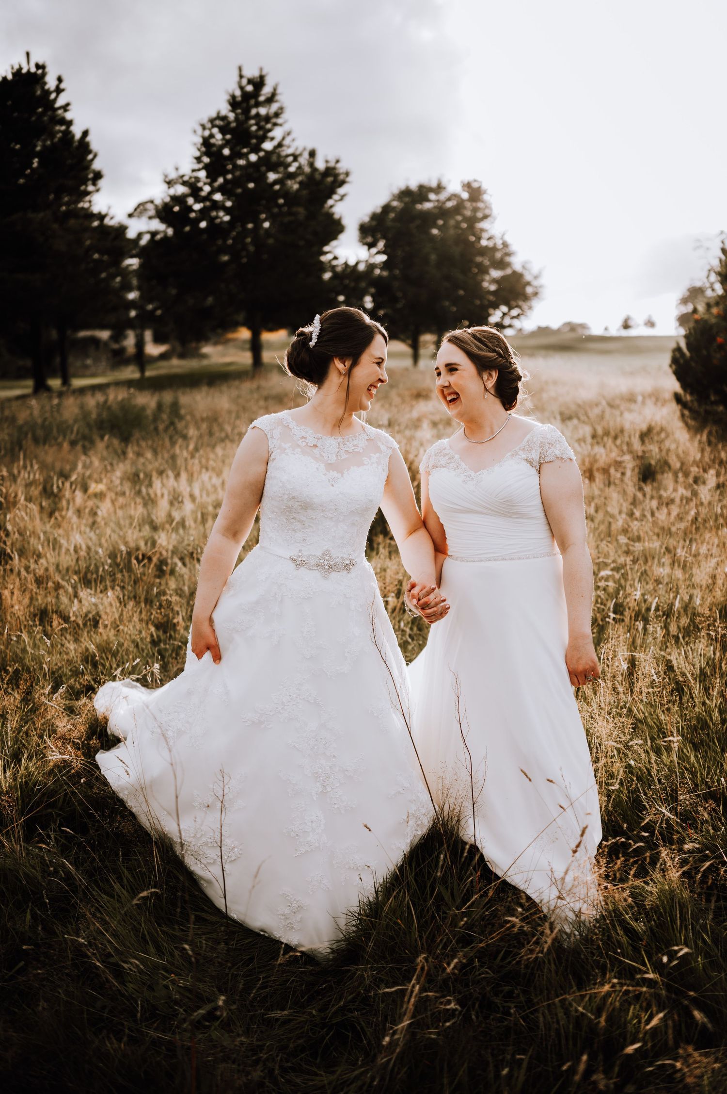 Aberdeen Wedding Photography. Two people in white wedding dresses walk through tall grass at golden hour.