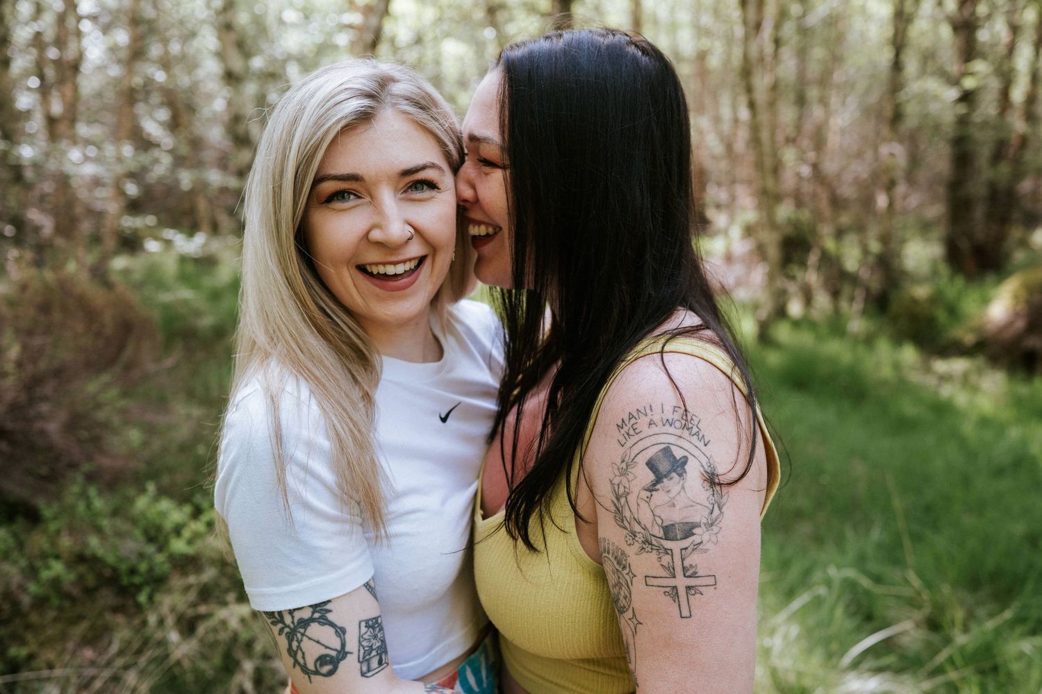 Engagement photography session Aberdeen. Two friends share joyful moments in a wooded area while wearing casual summer outfits.