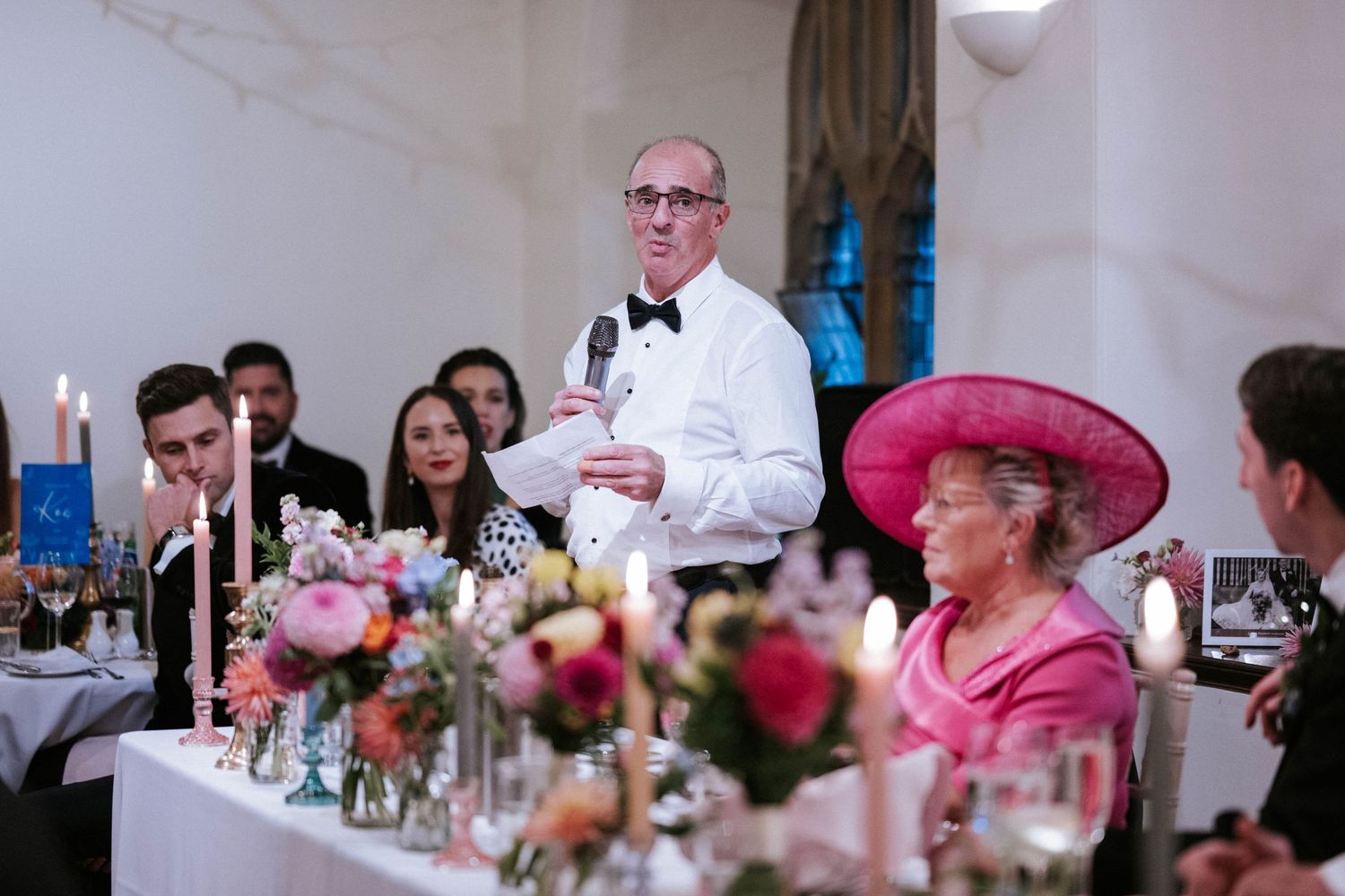 Wedding guests enjoying dinner conversation at elegantly decorated reception tables.
