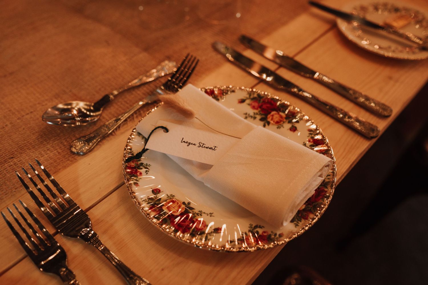 Elegant place setting with decorative plate and silverware on textured tablecloth with warm lighting.