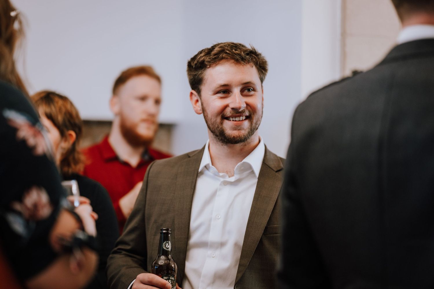 Guest enjoying drinks and conversation at an indoor wedding reception.