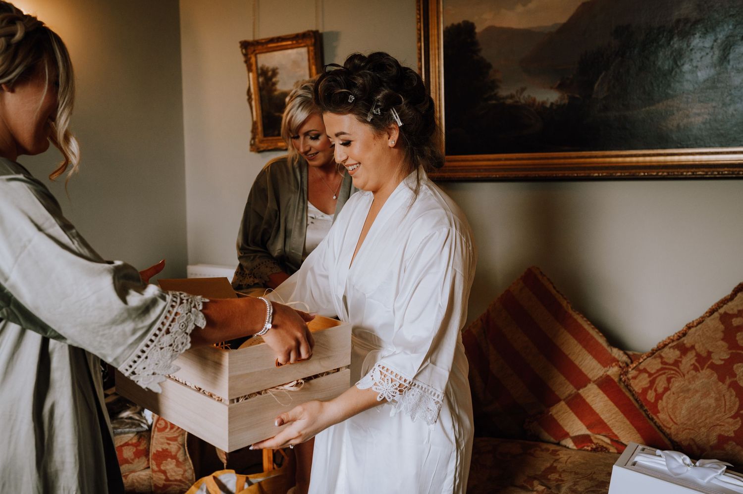 A candid moment of wedding morning preparations with gift opening in a cozy room.