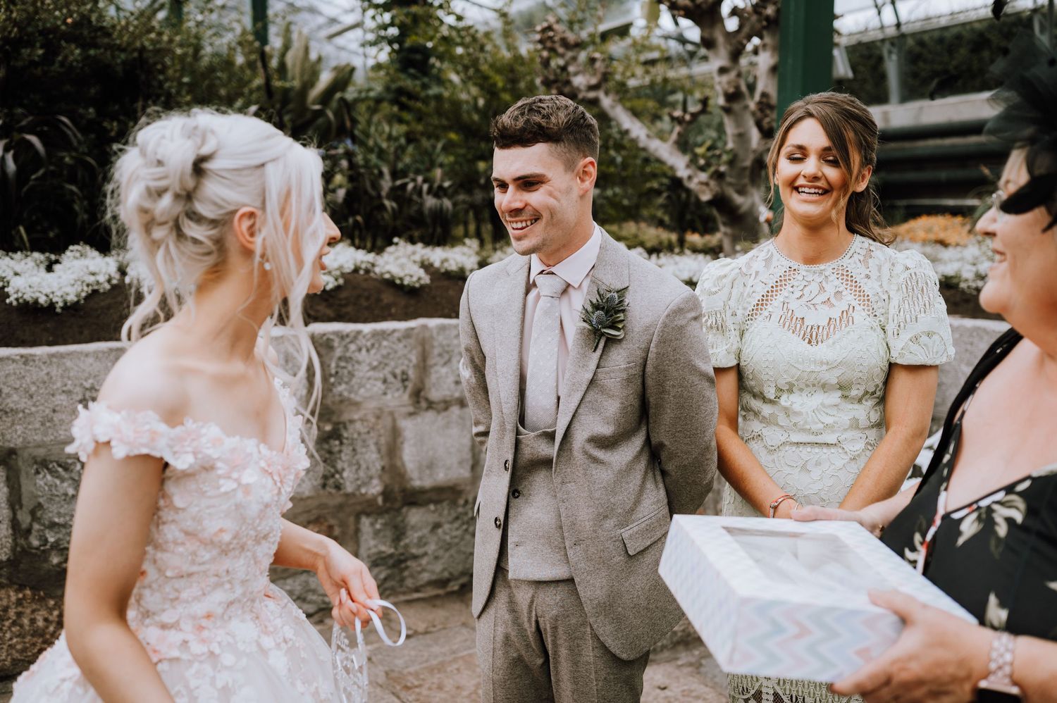 Wedding party members share laughter during an outdoor garden celebration.