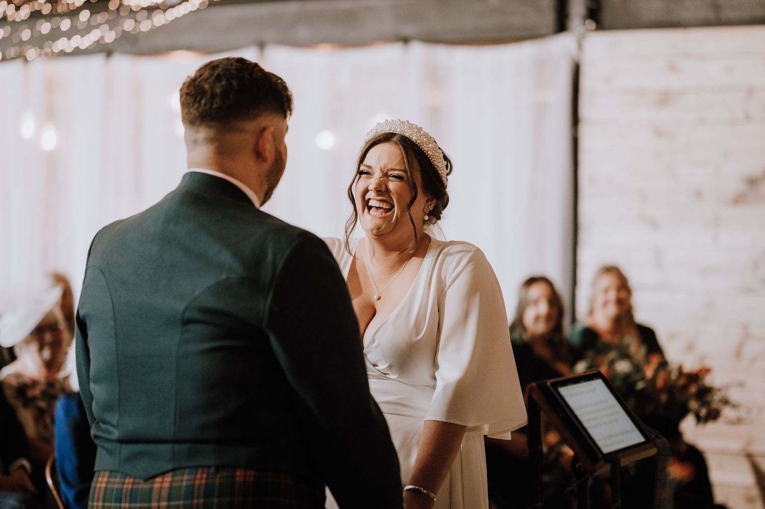 Joyful moment shared during wedding ceremony in bright indoor venue with white walls.