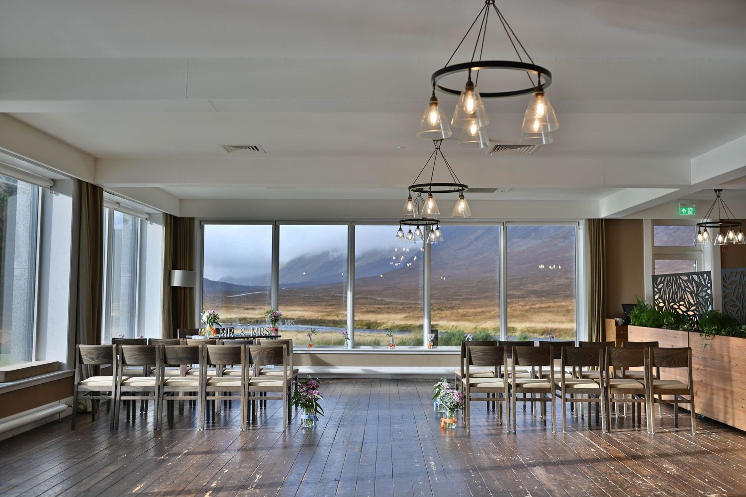 A modern reception venue with large windows overlooking Scottish highlands and mountains.