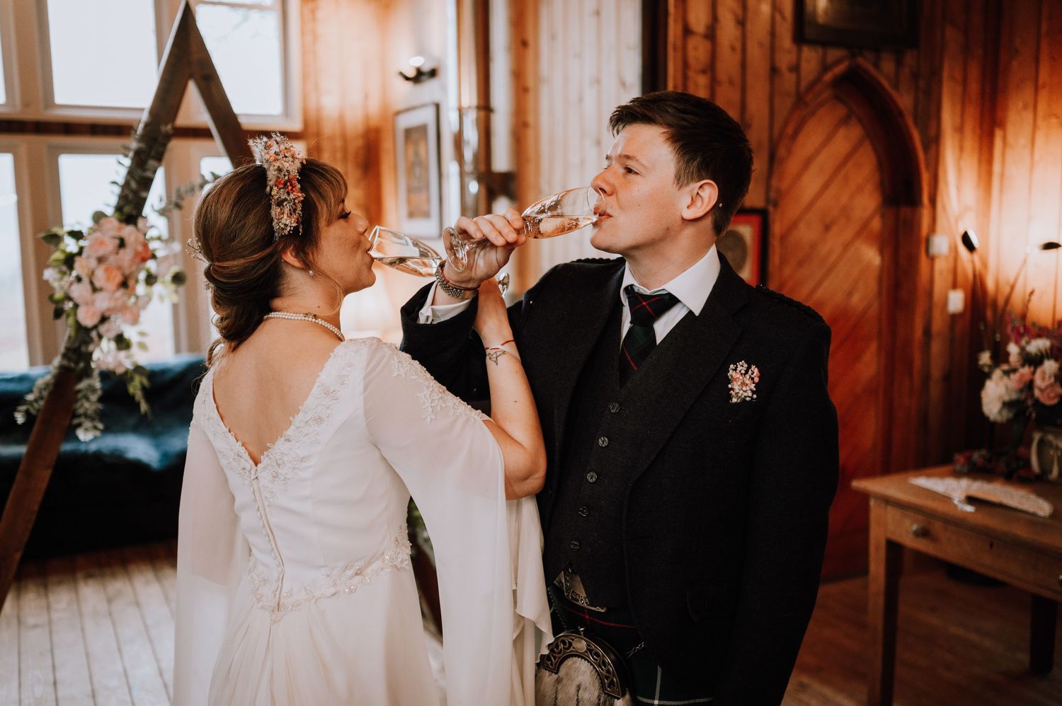 Couple shares a drink together during wedding celebration in wooden interior.