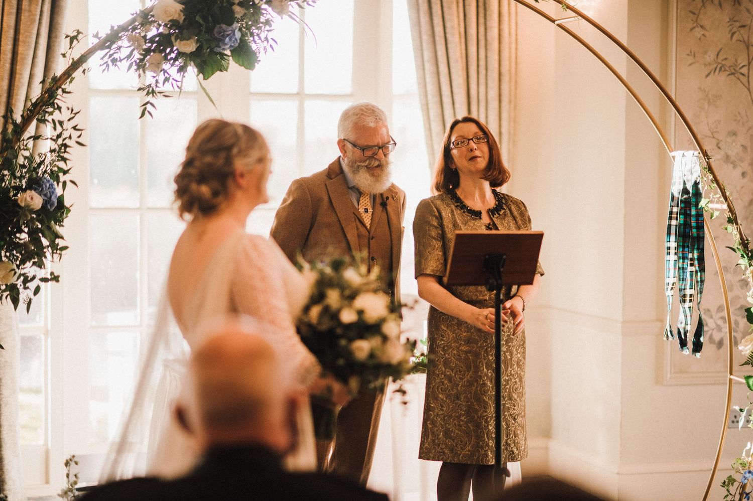 Intimate indoor wedding ceremony with natural light streaming through elegant windows.