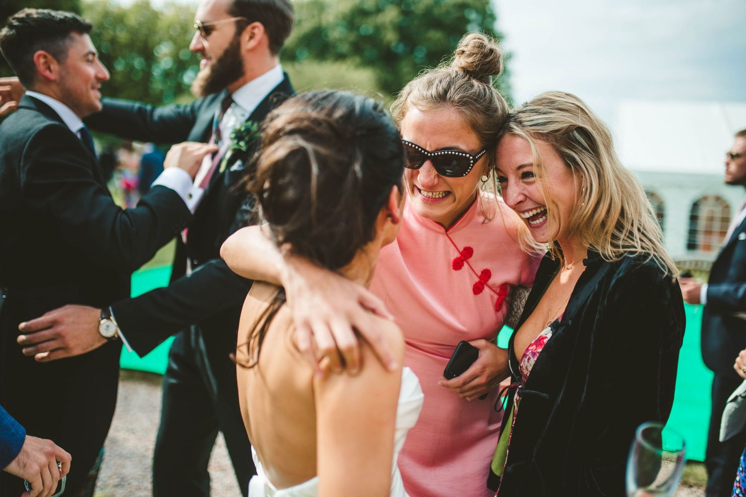 Guests share joyful laughter and hugs during outdoor wedding reception.