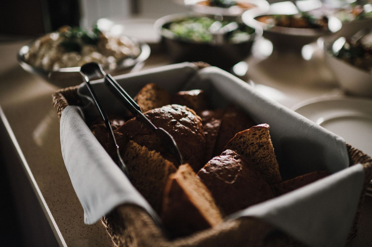 Dark bread loaves arranged in a serving dish with cloth napkin.