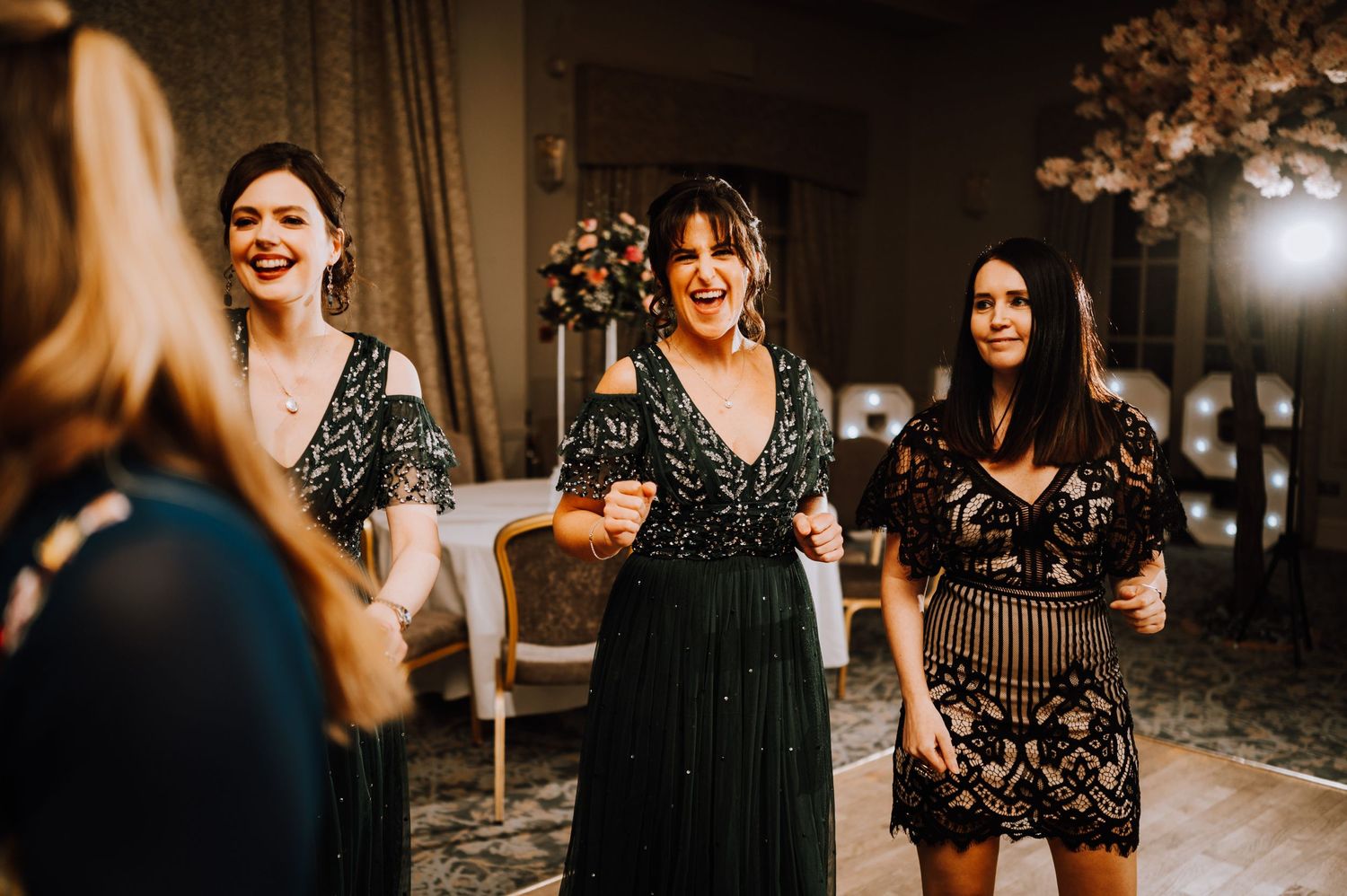 Friends celebrating at an evening party with decorative lighting and elegant dresses.