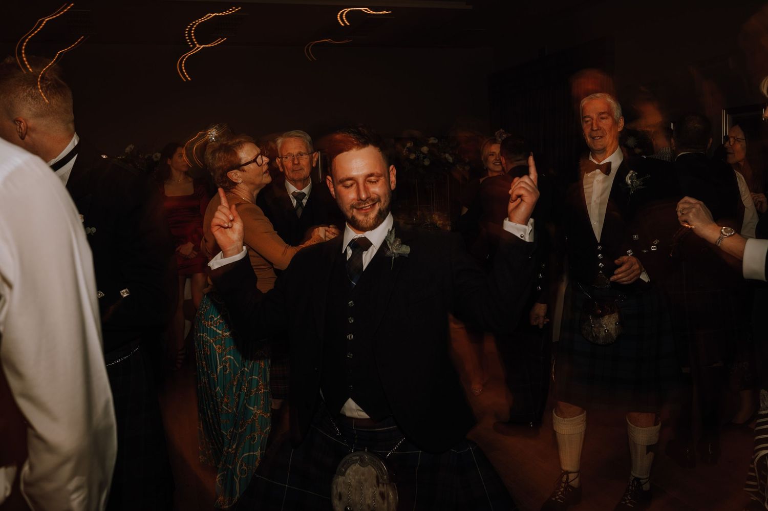 Guests enjoying themselves on a dark dance floor at an evening celebration.
