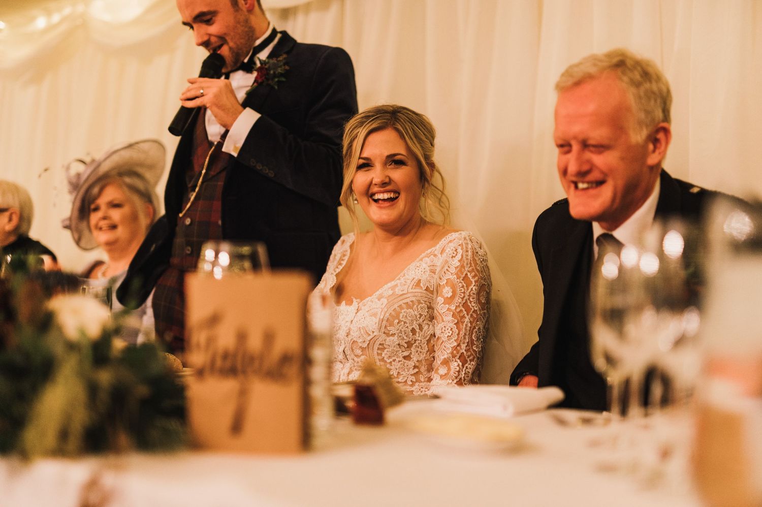 Reception table scene during speeches with elegant decor and warm lighting.