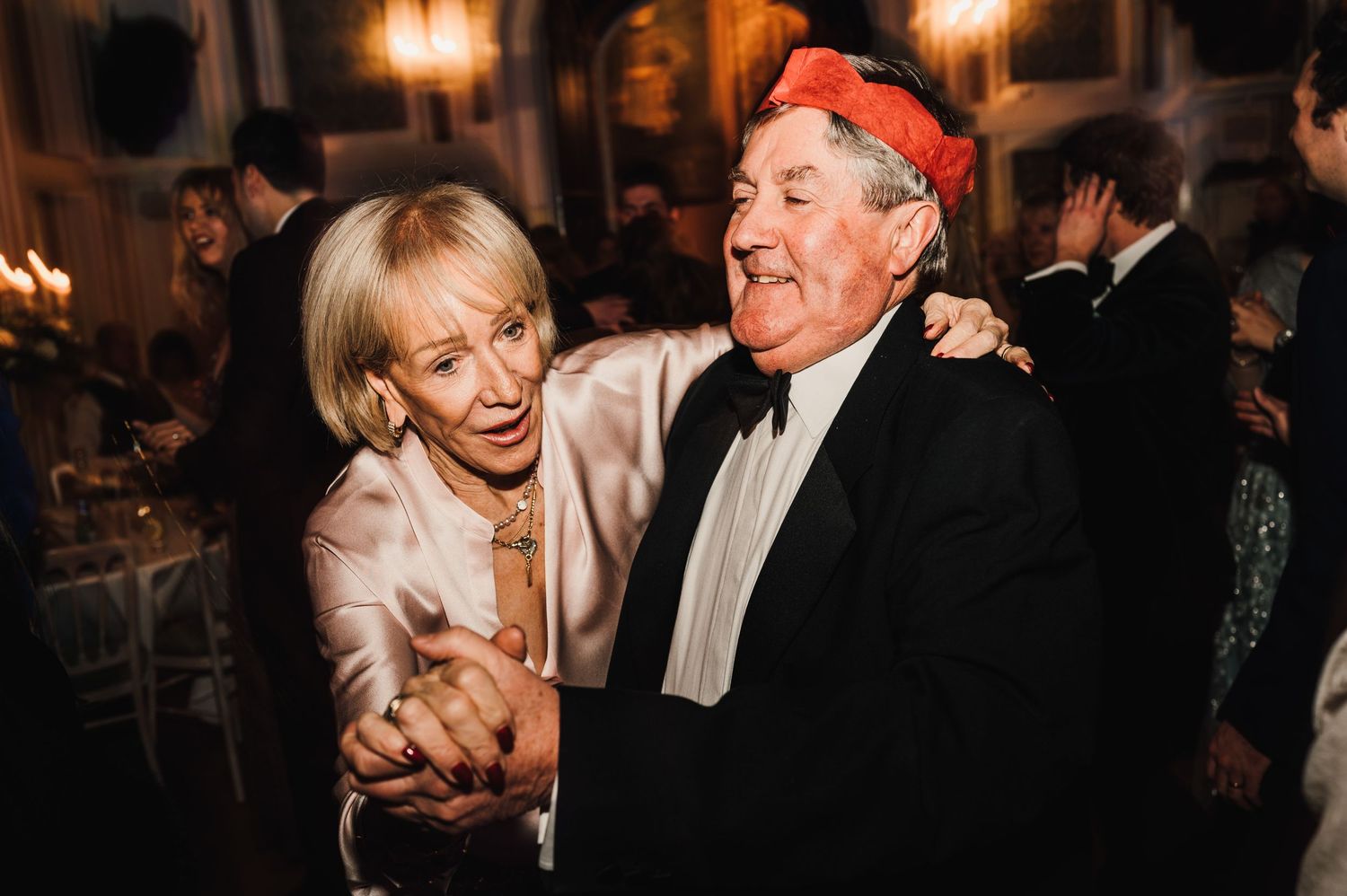 A joyous dance at an elegant evening wedding reception with dancing guests enjoying themselves.