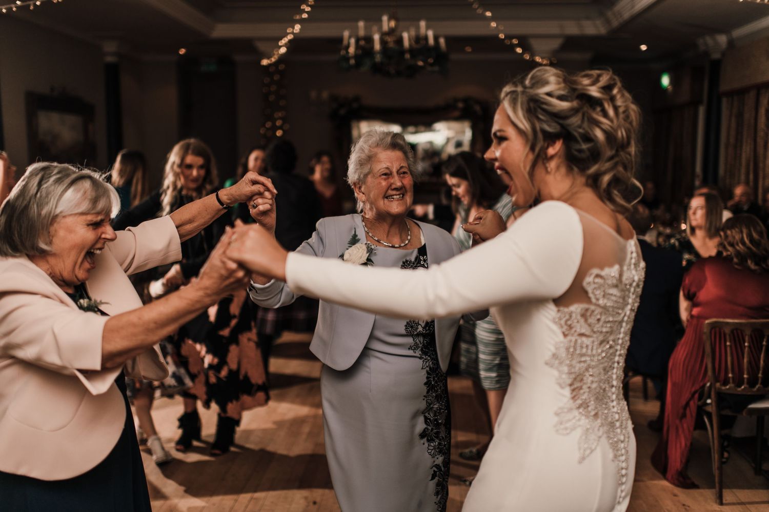 A joyous dance celebration at a wedding reception with guests in formal attire.
