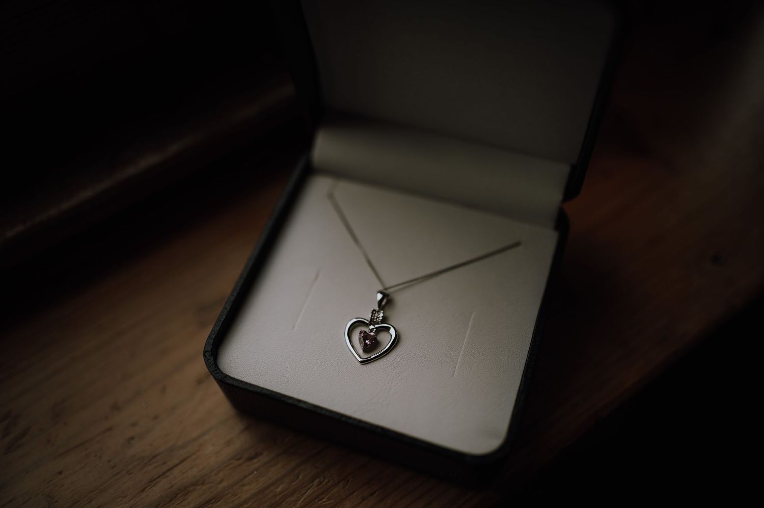 Close-up of delicate silver anchor necklace pendant in dark jewelry box.