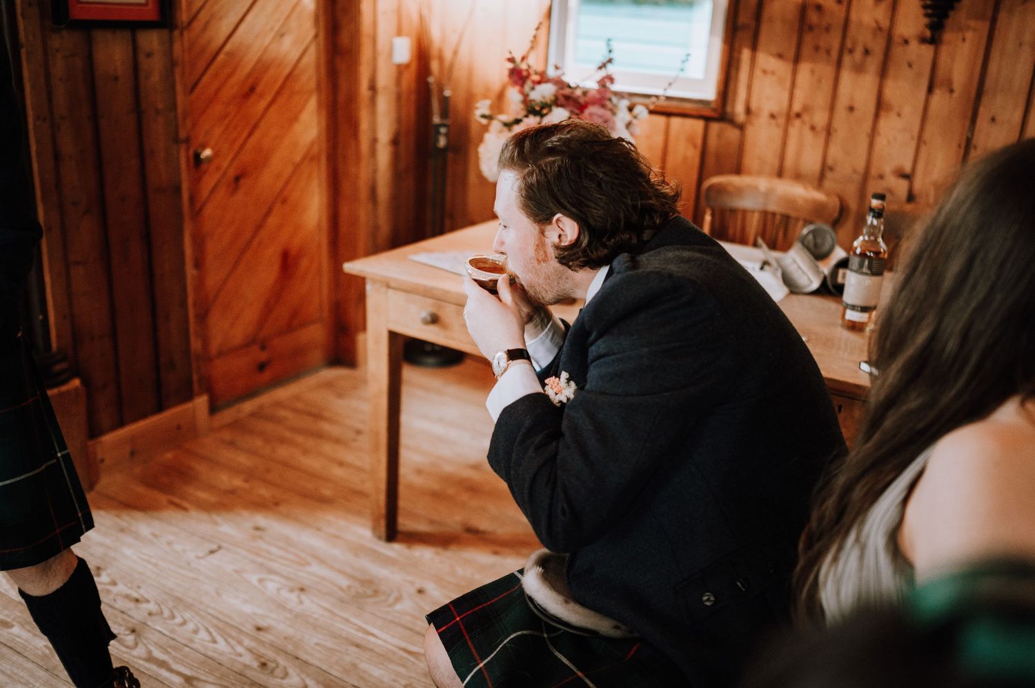 Someone in formal attire becomes emotional in a rustic wooden interior setting.