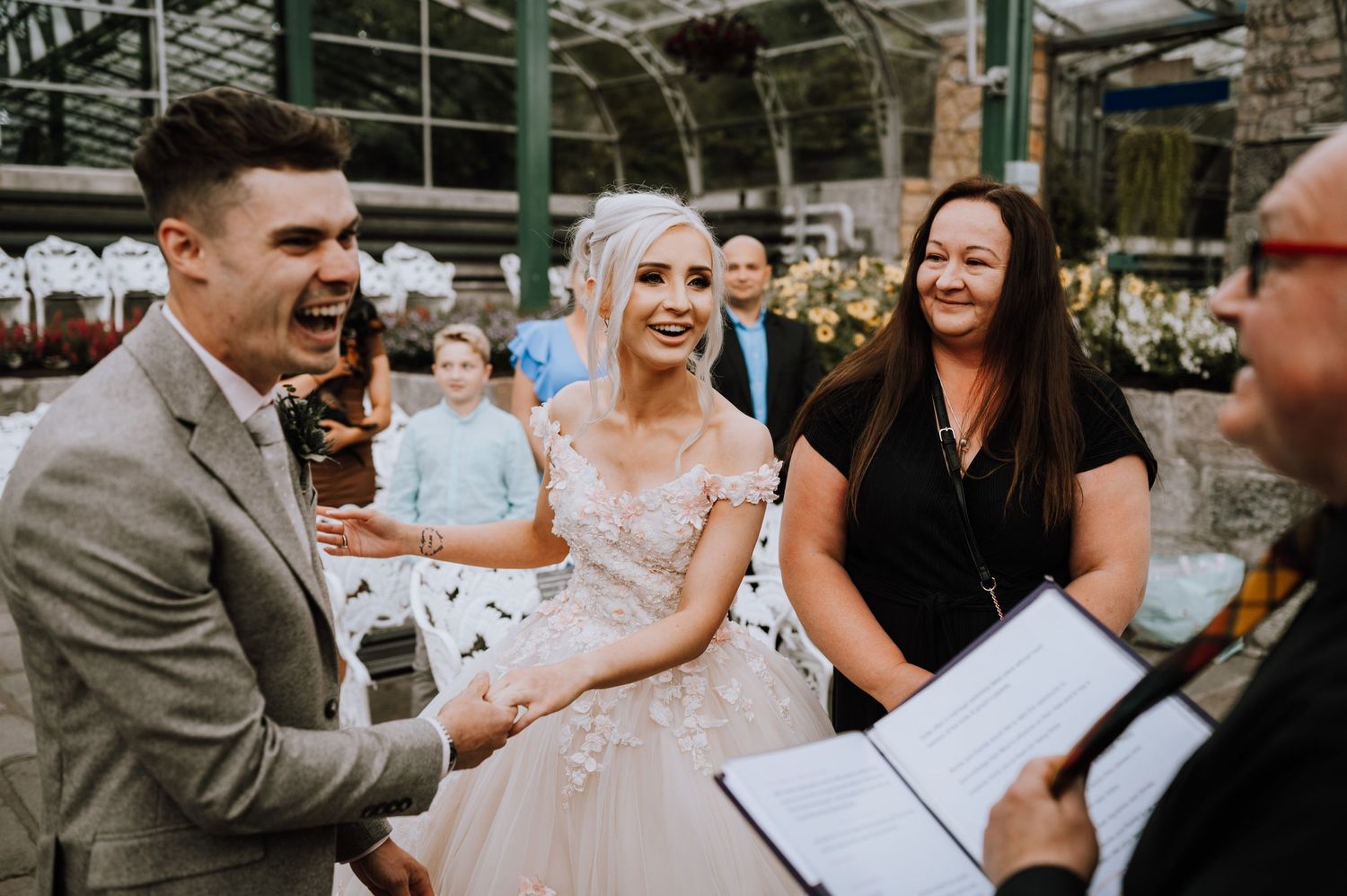 A candid moment during a wedding ceremony in a beautiful greenhouse setting.