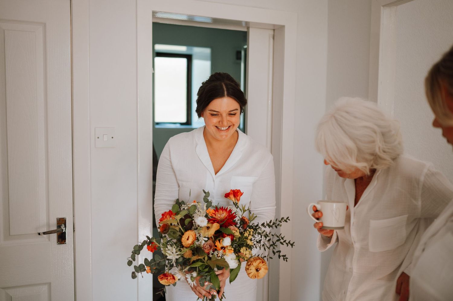 A person enters a doorway carrying a vibrant bouquet of flowers and greenery.