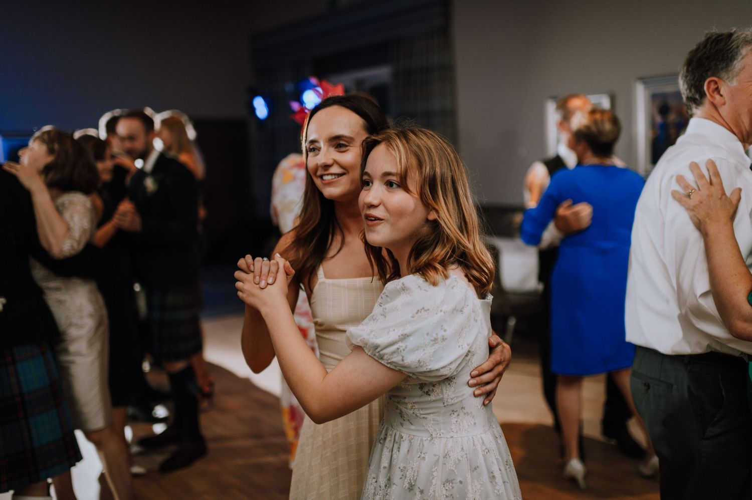 Wedding guests embrace while dancing and celebrating at a reception.