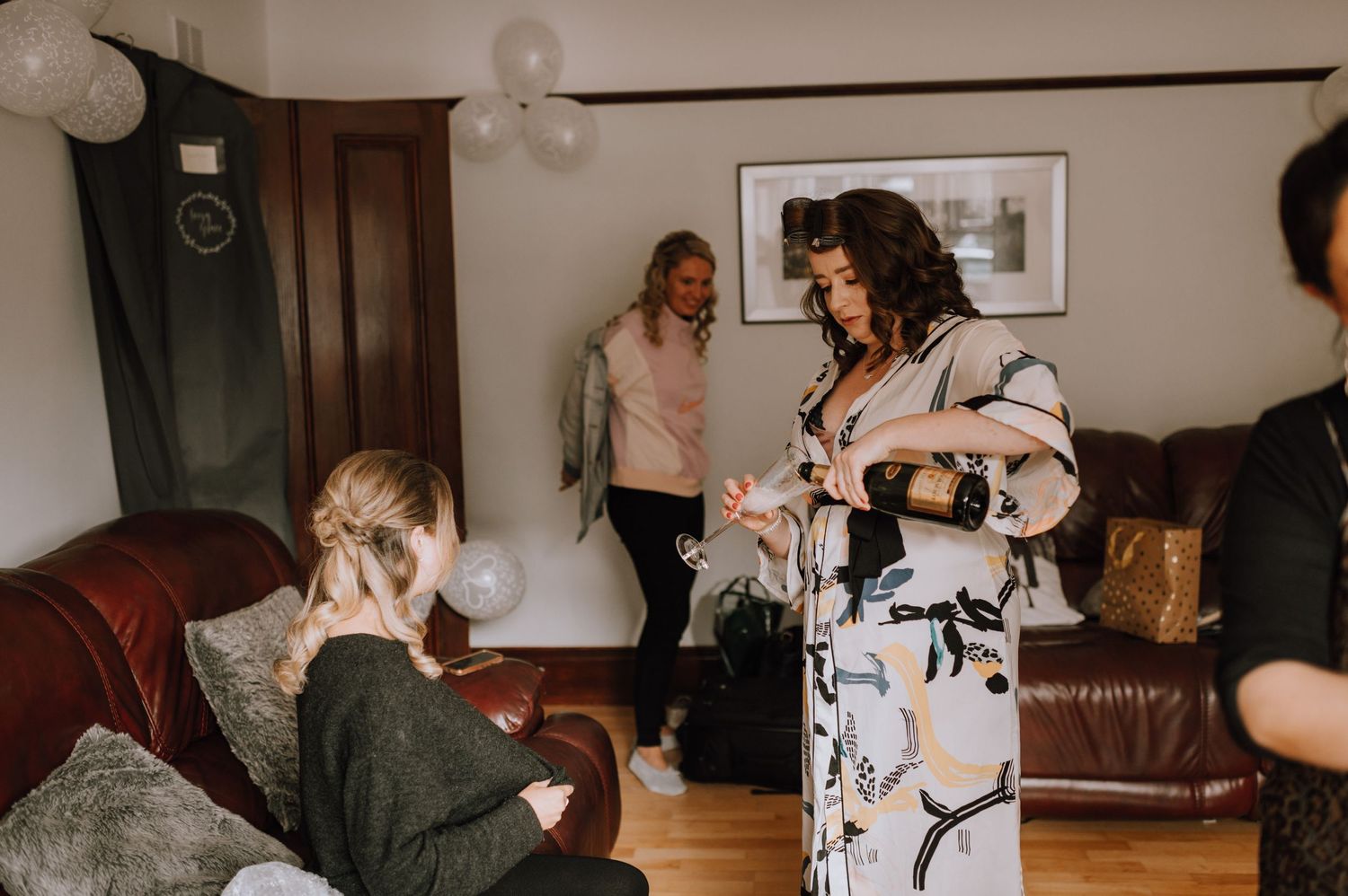 Casual gathering in living room with brown leather couch and wooden furniture.