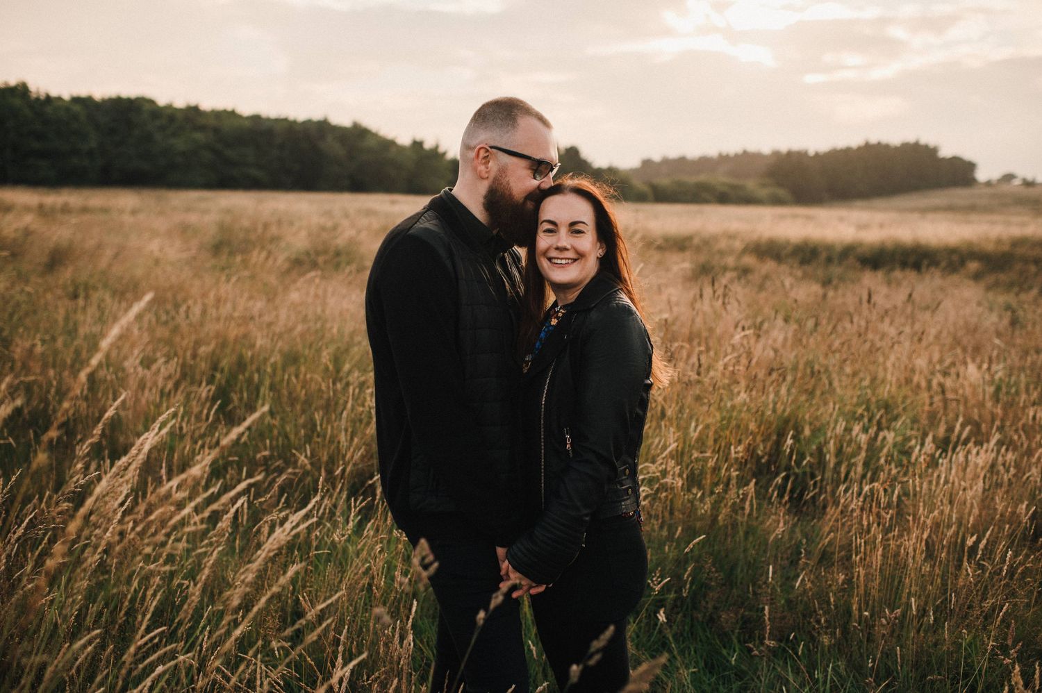 A joyful moment shared between two people in a golden field at sunset.