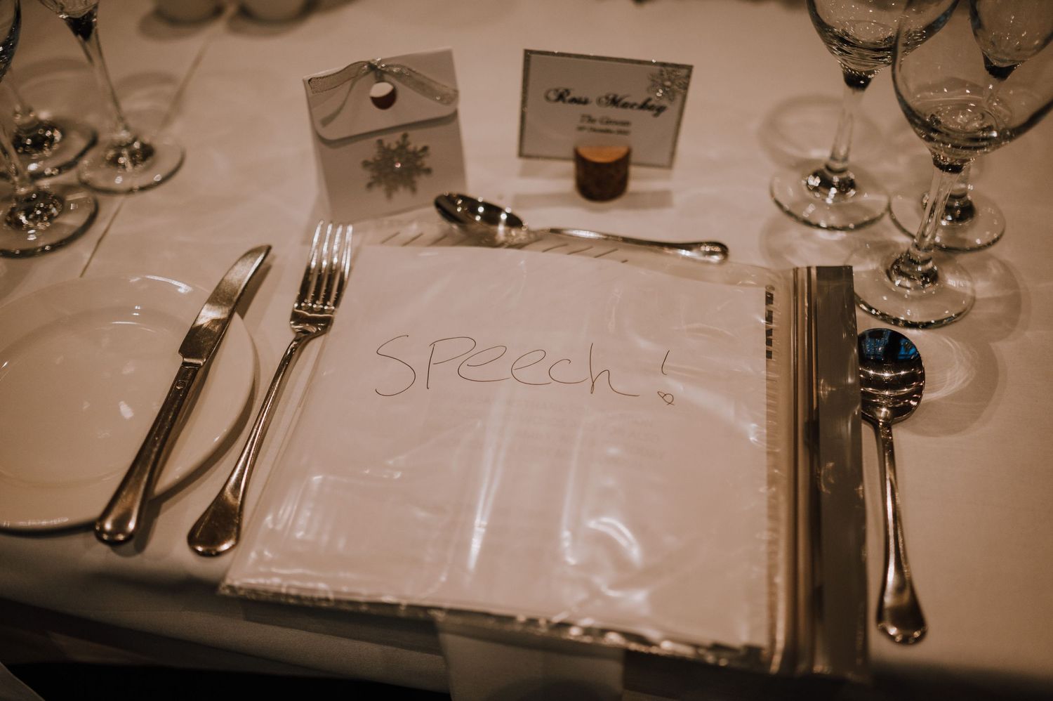 Elegant place setting with silverware and place cards at formal dinner.