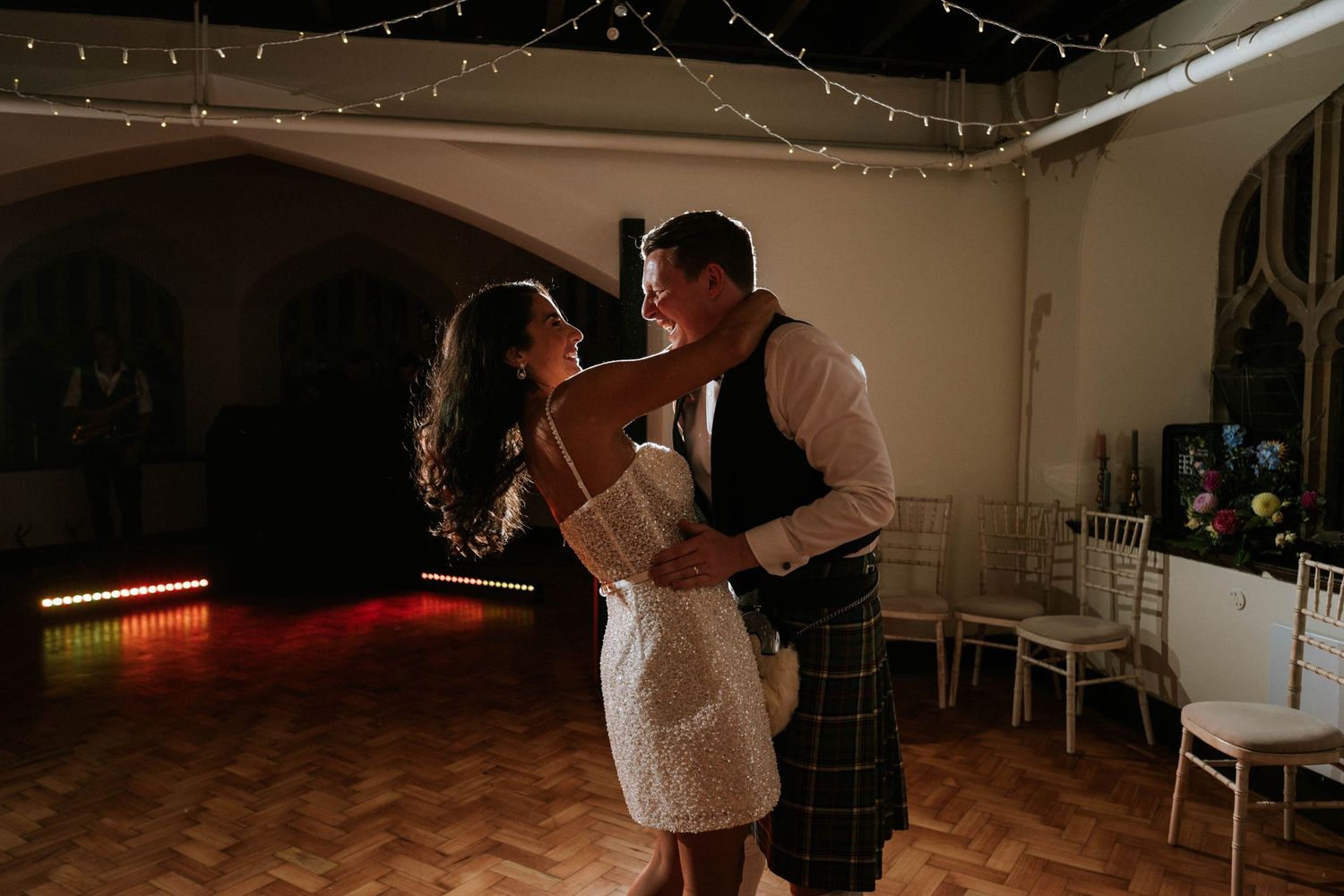 Couples slow dancing at an intimate wedding reception with fairy lights decorating the ceiling.