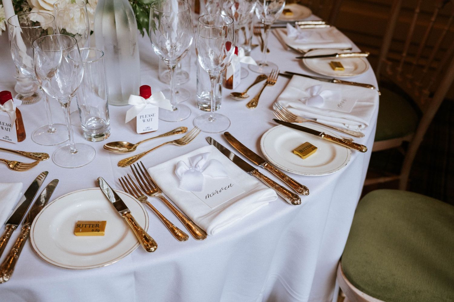 Elegant table settings with white linens and gold cutlery at a formal wedding reception.