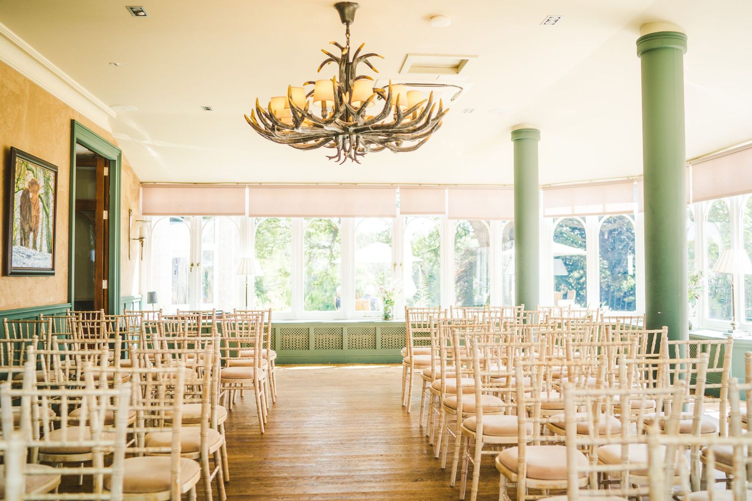 Elegant wedding reception venue with rustic chandeliers and rows of white chairs.
