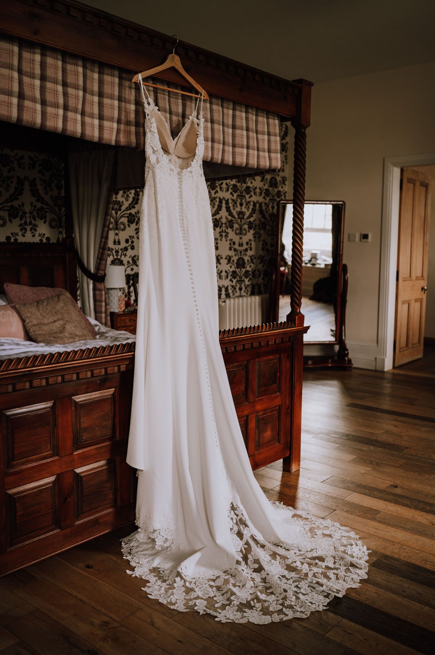 Aberdeen Wedding Photography. White lace wedding dress hanging on display in a rustic wooden bedroom.