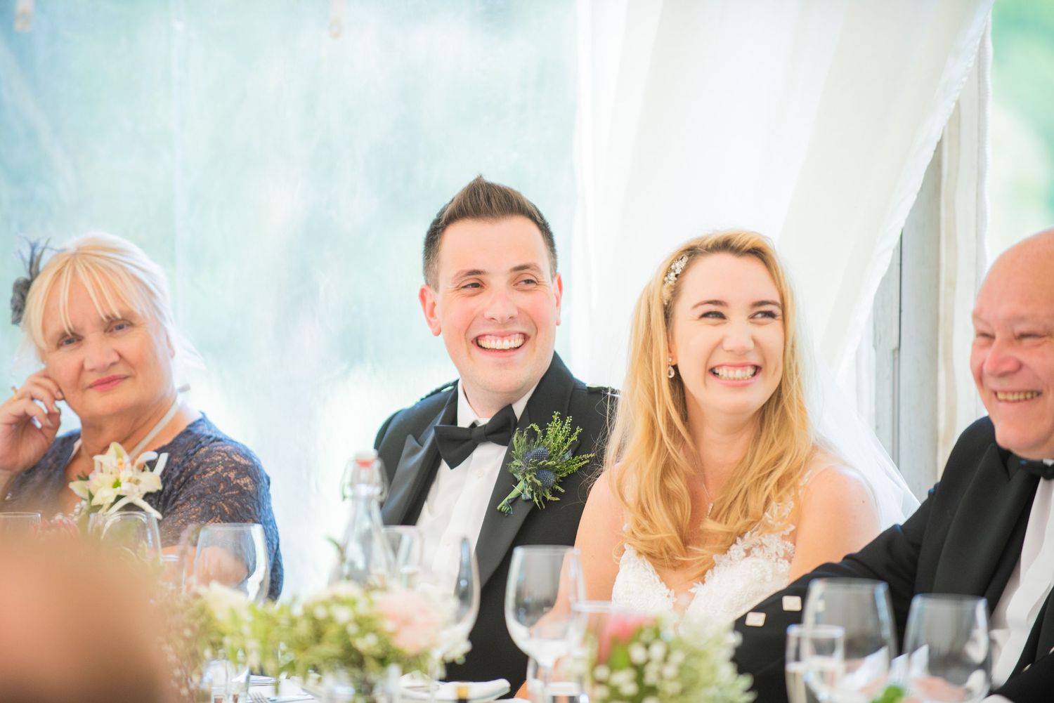 Wedding guests enjoying conversation at tables during a bright reception celebration.