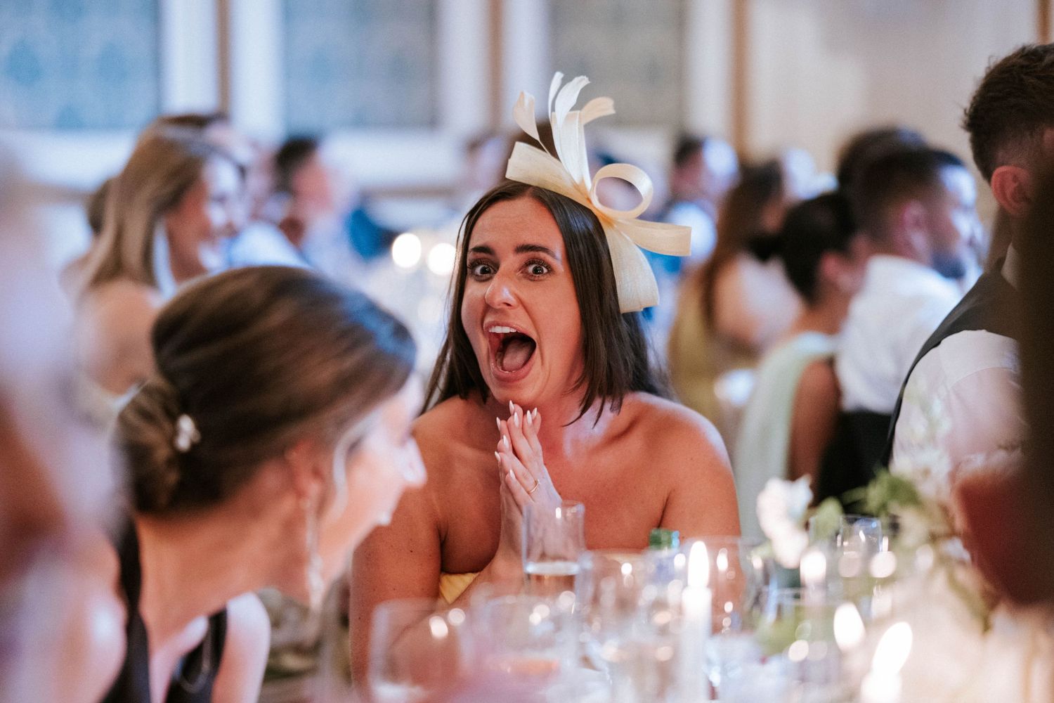 Wedding guests celebrating with joyful expressions during reception dinner.