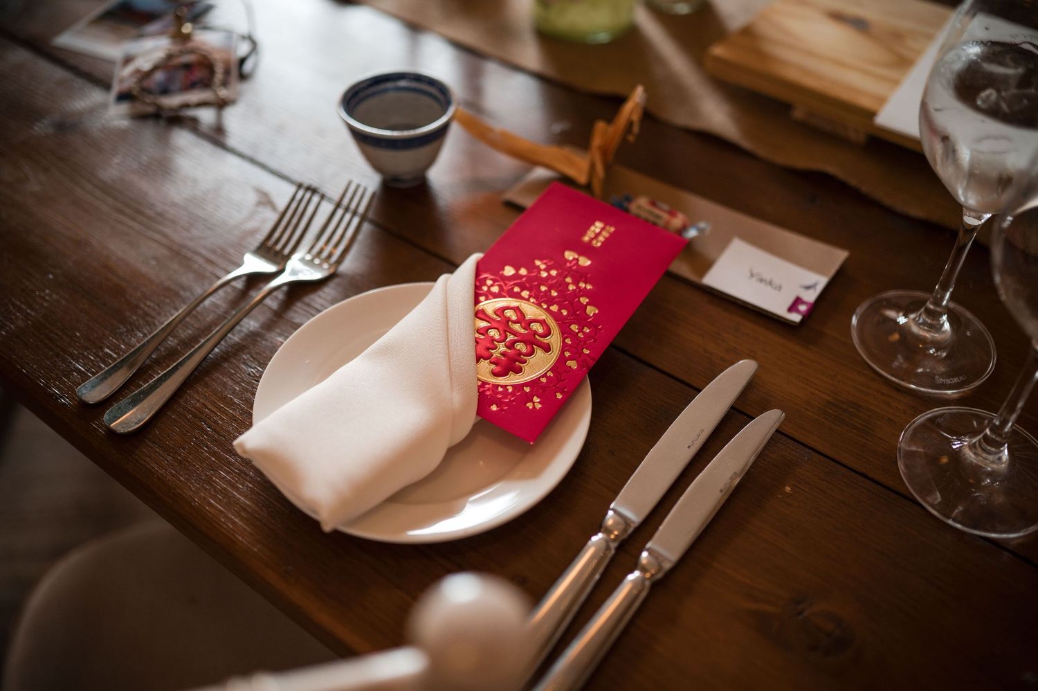 Elegant place settings with red napkins and silverware on wooden tables.