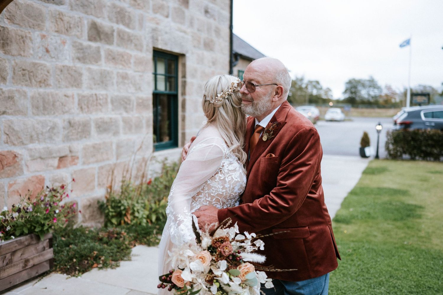 Wedding guests gather outside a rustic stone building with floral arrangements and decorative touches.